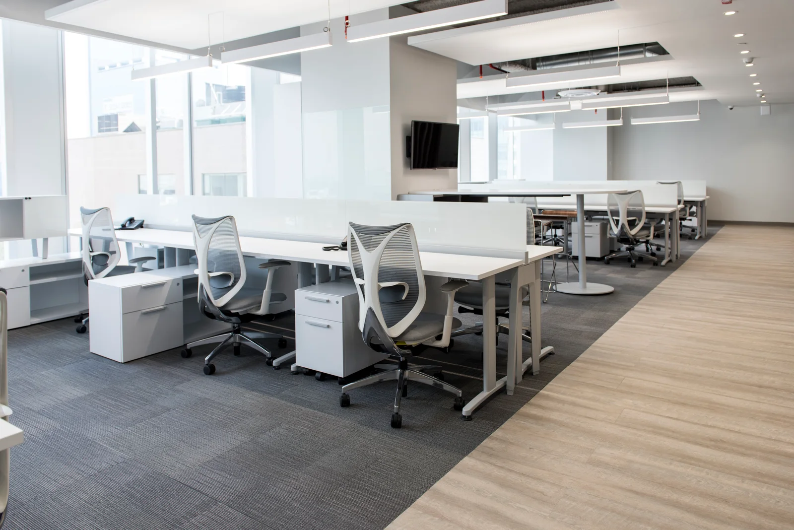 Área abierta de oficinas con estaciones de trabajo y sillas ergonómicas