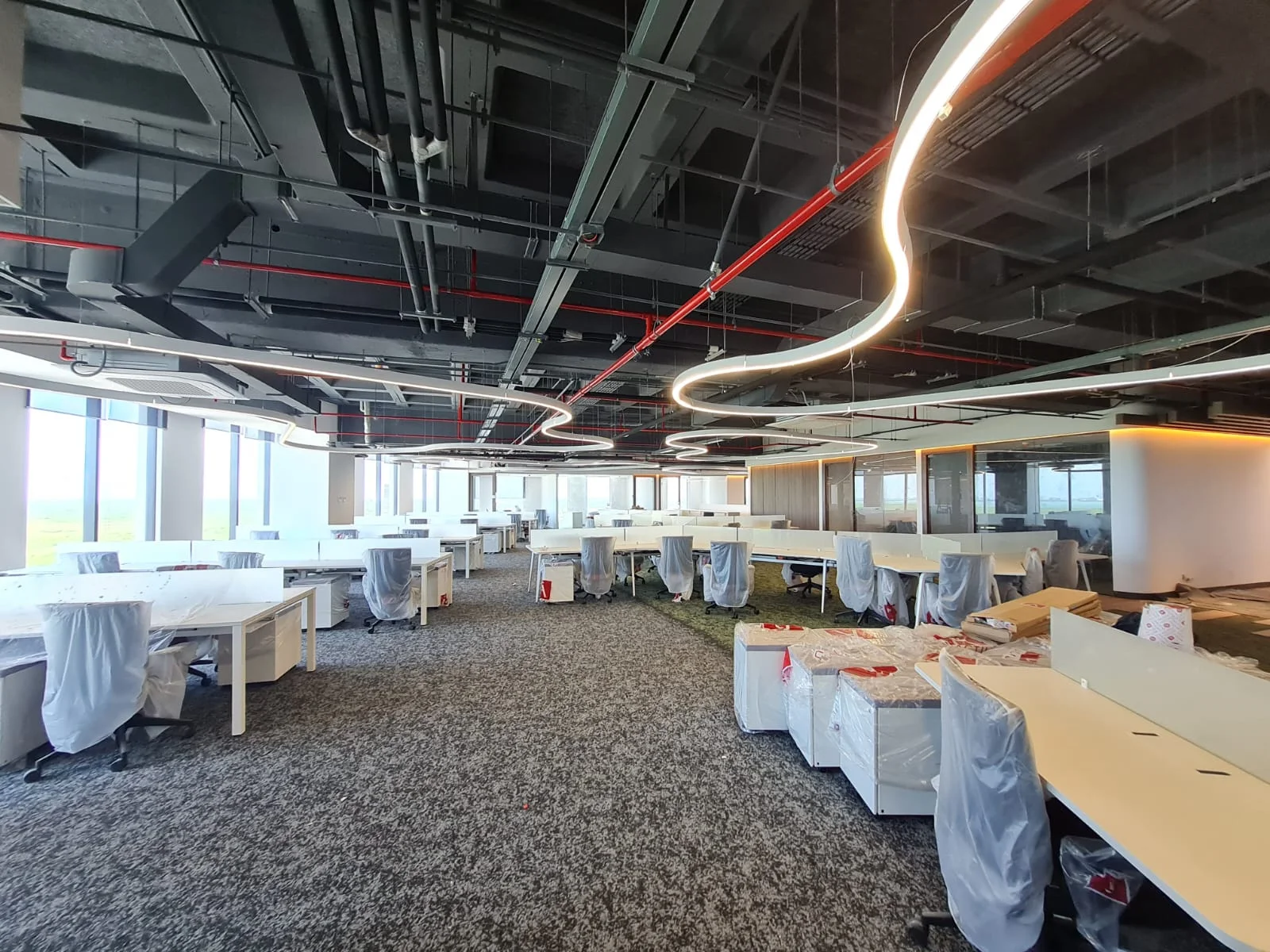 Área de oficinas durante la obra con instalaciones expuestas y mobiliario protegido